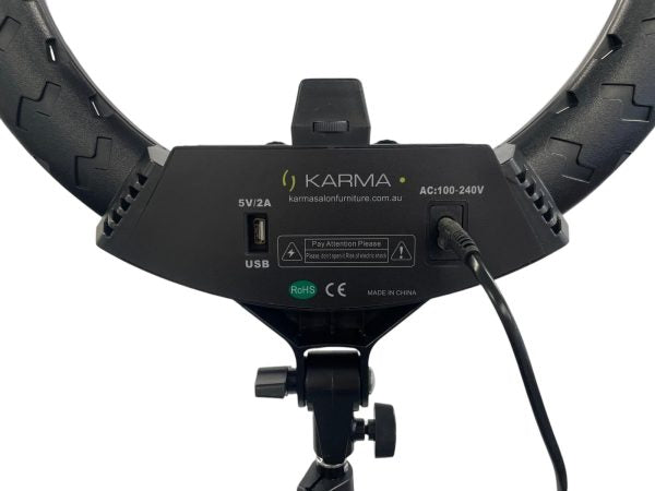 The Karma Ring Beauty Light is an 18-inch black LED ring light mounted on an adjustable floor tripod stand with a built-in central mirror interface.