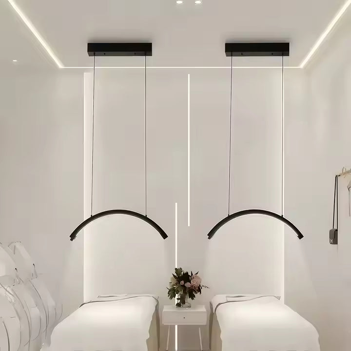 The Karma Ceiling Mounted LED Half Moon Light  is a 28-inch overhead curved arc treatment lamp suspended by adjustable dual-wire cables.