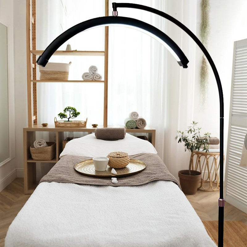 The Karma Half Moon Beauty Light is a black 28-inch wide curved arc treatment floor lamp featuring a low-profile flat base and internal hidden cable management.