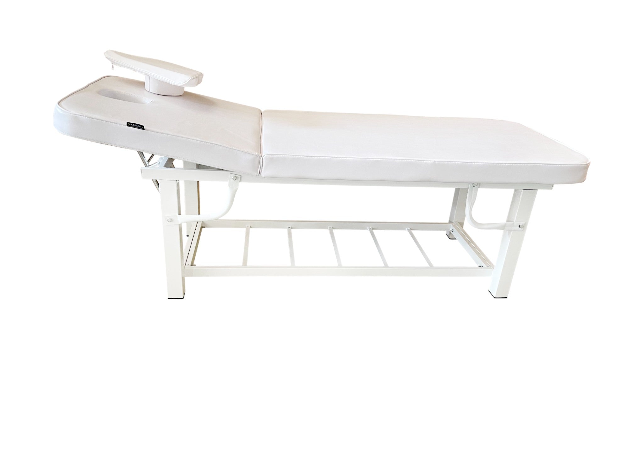 The Karma Napier Beauty Bed, featuring a raised backrest, removable face pillow, and a heavy-duty white steel frame with an integrated storage rack.