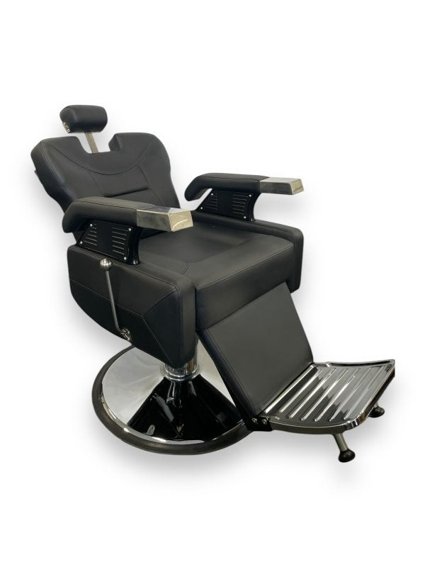 The Karma Runcorn is a reclining black barber chair featuring a heavy-duty chrome hydraulic base, adjustable headrest, and ergonomic footrest.