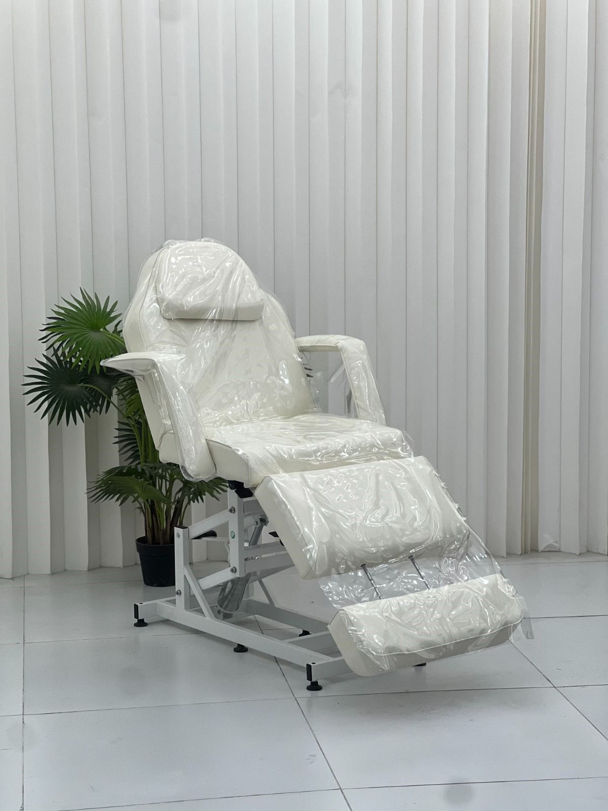 The Karma Universal Plastic Bed Cover  is a clear, 3-piece waterproof protector set fitted over a white electric treatment bed, showing headpiece, main body, and arm covers.